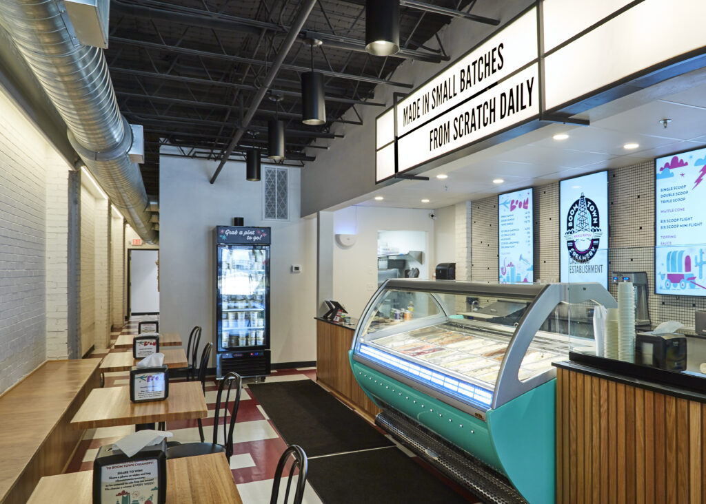 Interior of Boom Town Creamery, shows the ice cream case and counter as well as a booth and table with seating