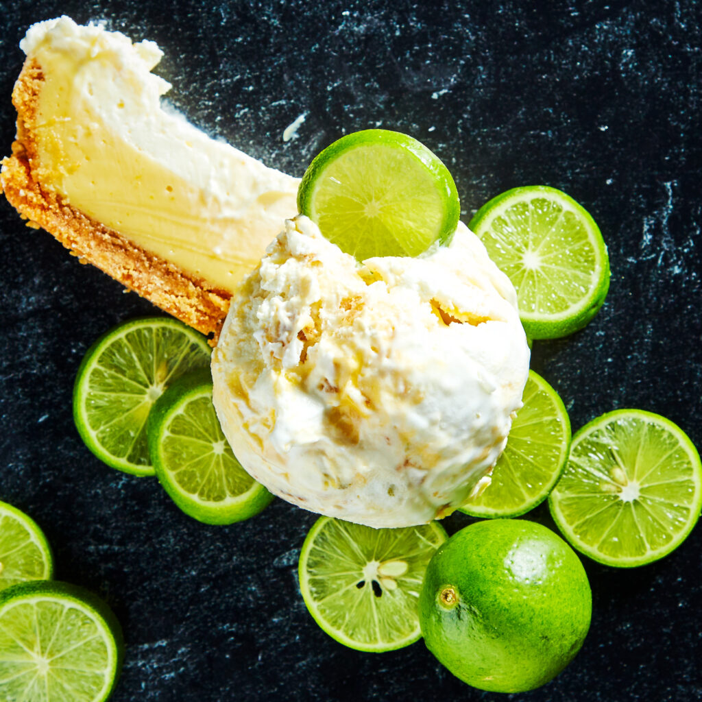 a single scoop of white and yellow key lime pie ice cream. surrounded by sliced limes