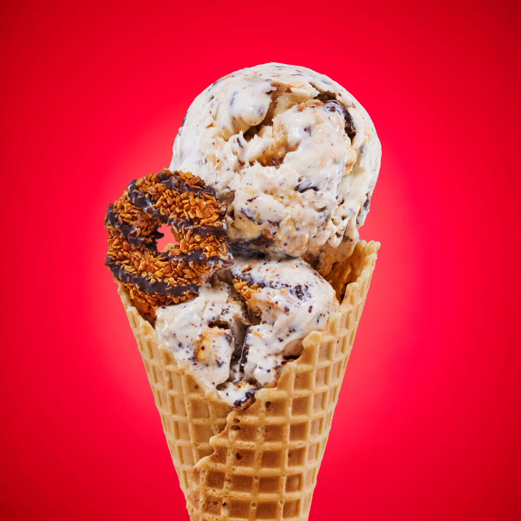 Double scoop of samoa girl scout cookie ice cream on a waffle cone with a cookie also on the cone